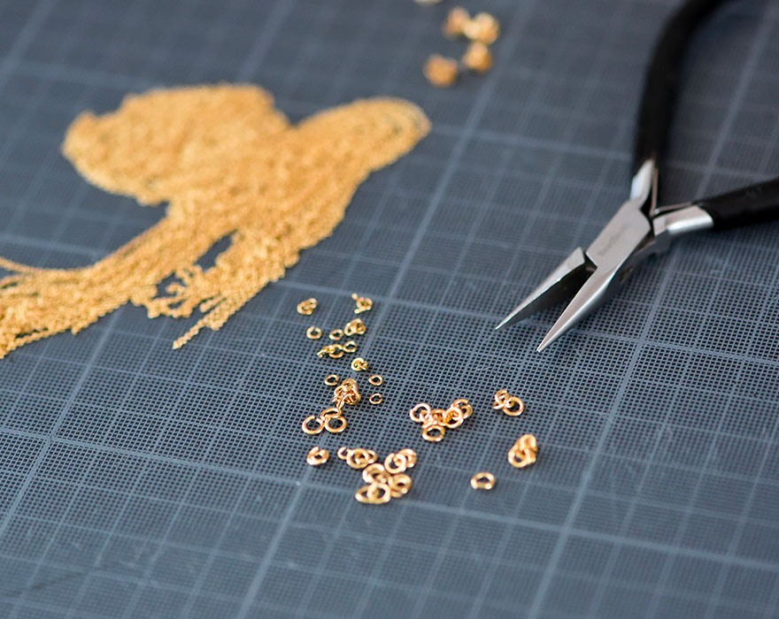 Scraps of gold brass and a jeweler's pliers on a cutting mat